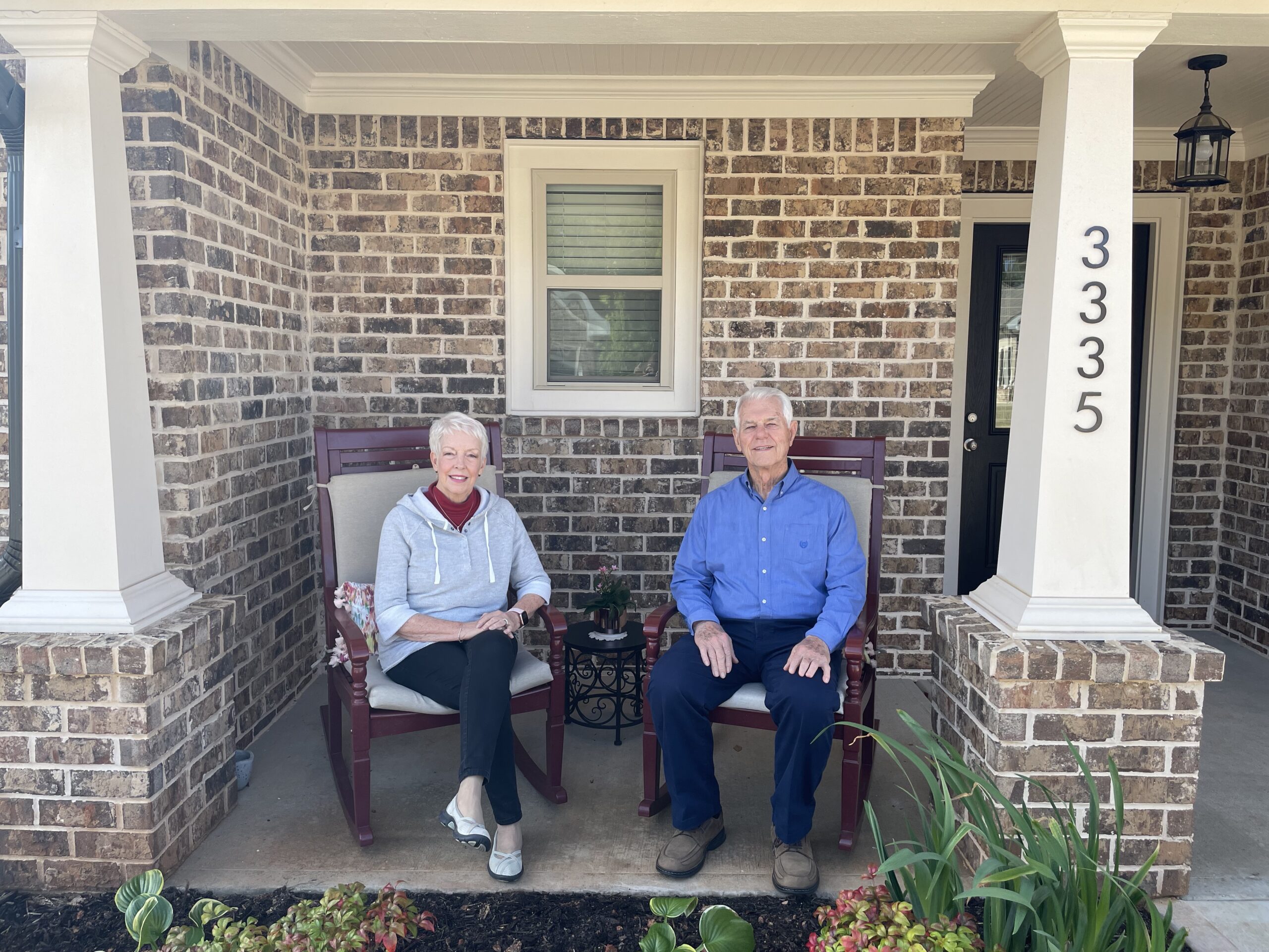 Two residents seated on a porch in rocking chairs