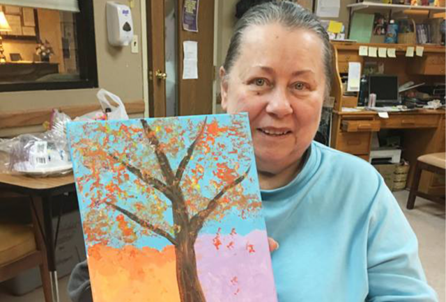 Resident showcasing a painting in a common area.