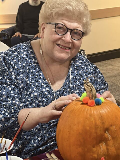 Resident decorating a pumpkin during an activity.