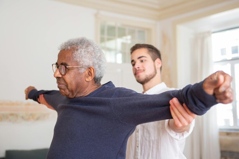 A caregiver assisting a senior man with exercises.