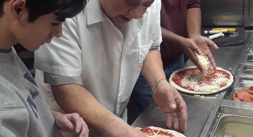 Residents and staff making pizzas together.