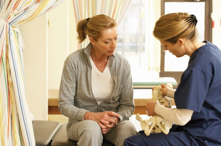 Therapist demonstrating spinal care to a resident.