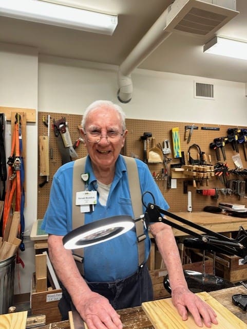 Senior resident smiling in woodworking shop.