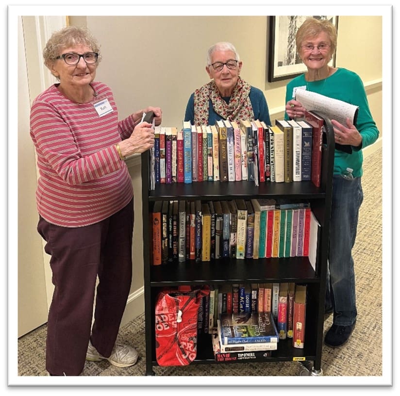 Three residents engaged with a book cart.