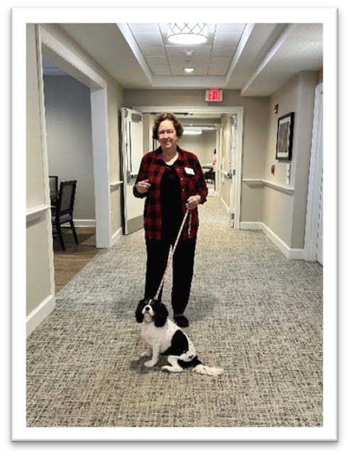 Staff member walking a dog in a hallway