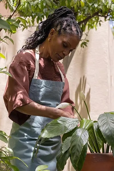 Woman tending to plants in a garden area.