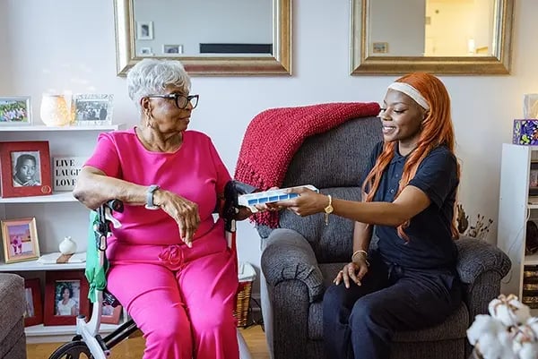 Caregiver assisting a resident in a cozy living area.