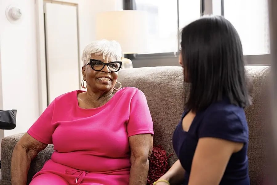 Senior resident smiling while talking with staff member.