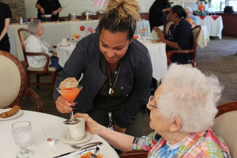 Staff serving food to a resident in the dining room.