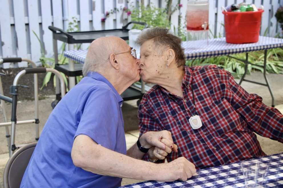 Two residents sharing a kiss in an outdoor setting.
