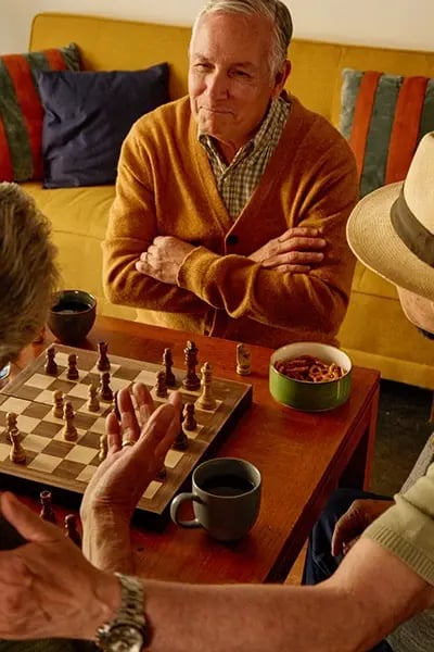 Seniors enjoying a chess game in a common area.