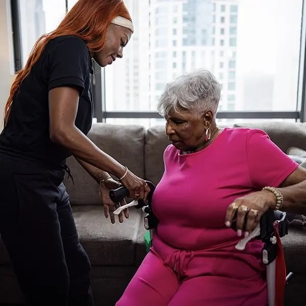Caregiver assisting an elderly woman in a cozy setting.
