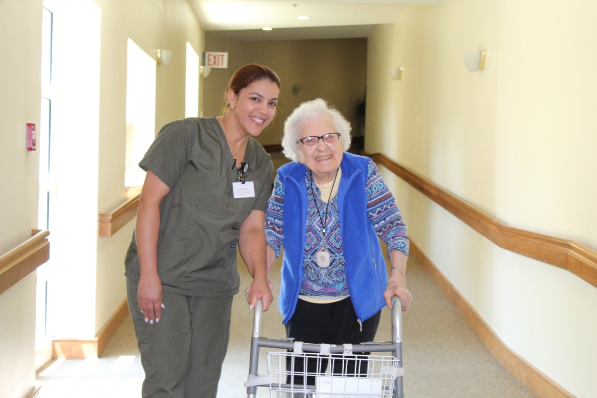 Staff member assisting a resident in a hallway.