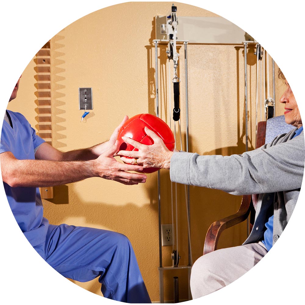 Therapist assisting resident with a red exercise ball