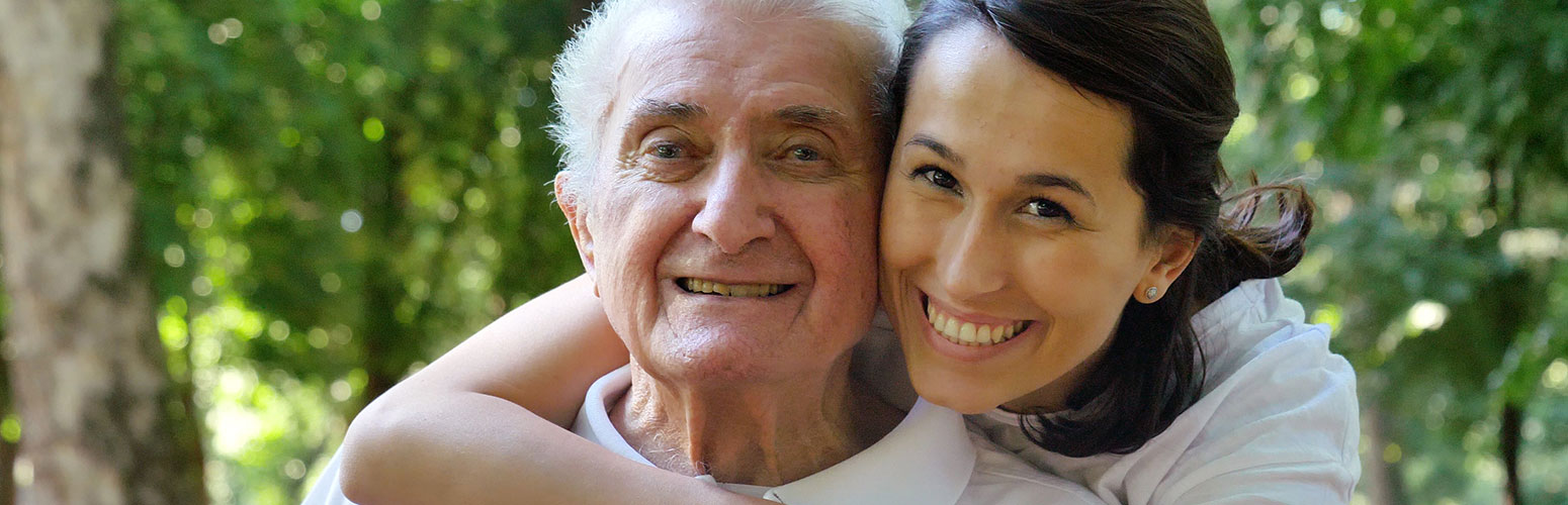 Senior man and caregiver smiling outdoors