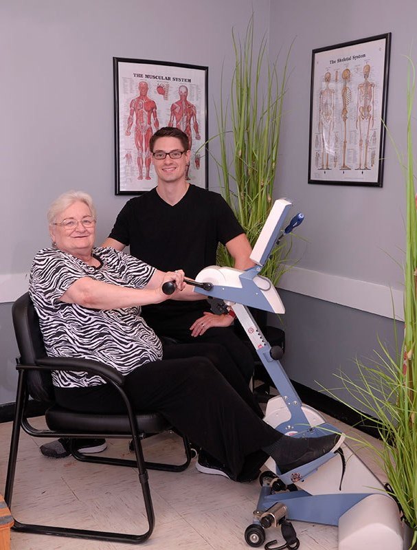 Senior resident using exercise equipment with staff support.
