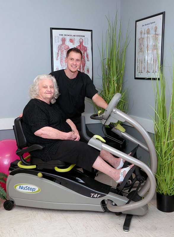 Resident using an exercise machine with staff assistance.