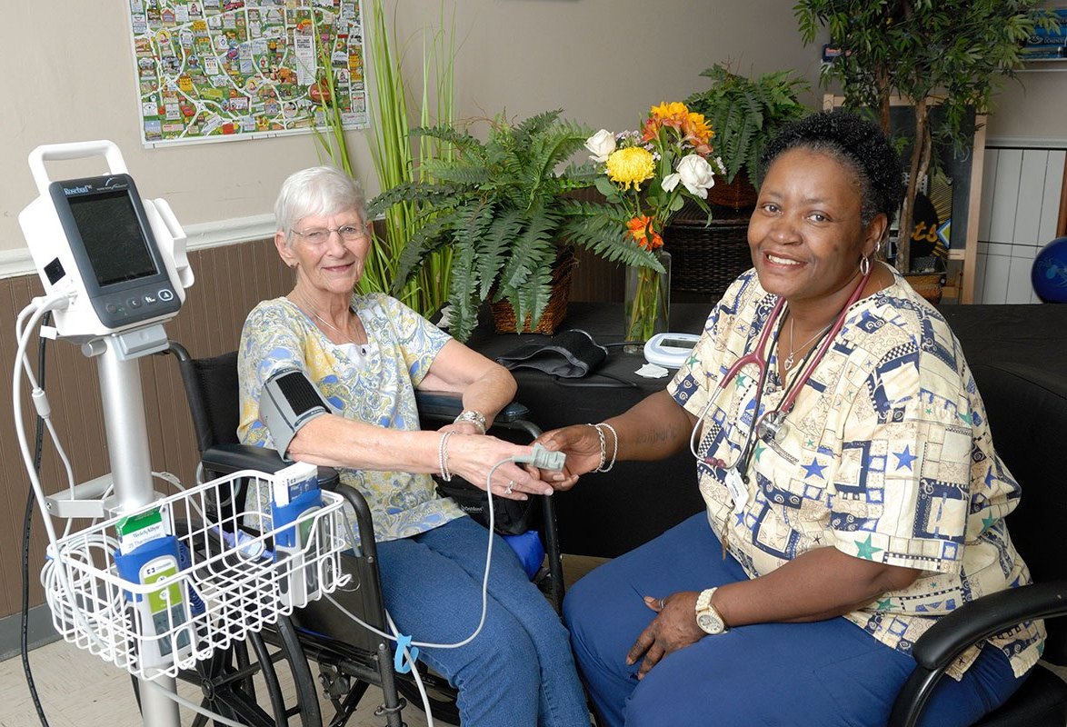 Healthcare staff assisting a resident in a facility.