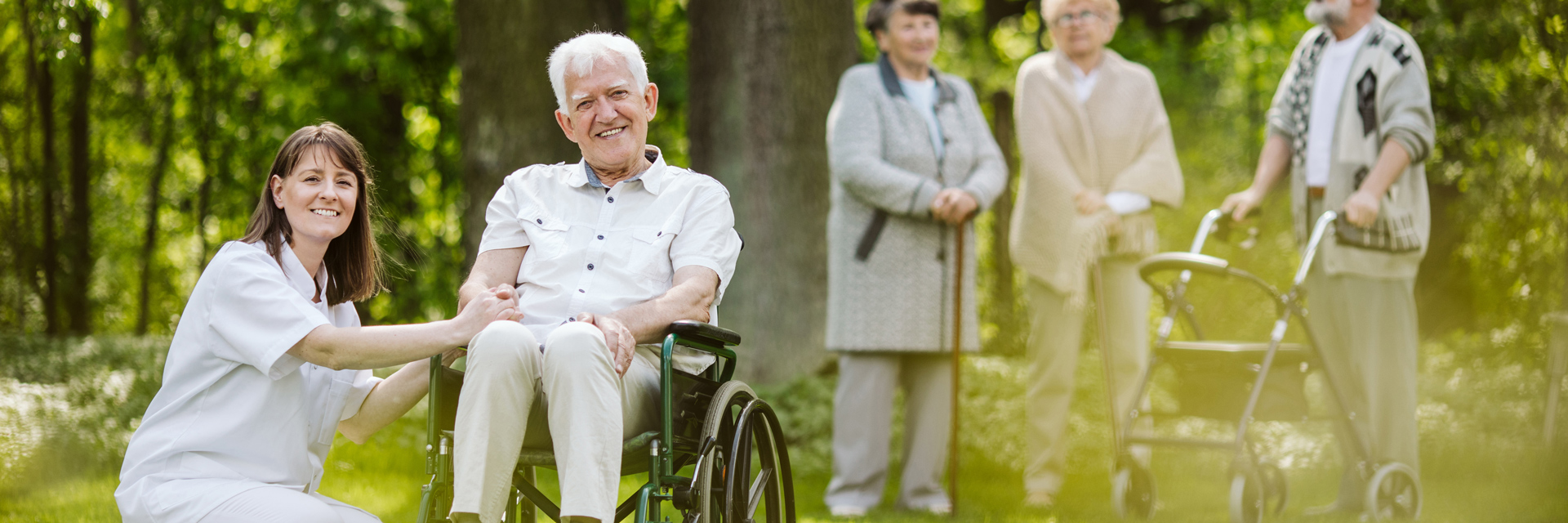 Senior resident enjoying time outdoors with caregiver and others.