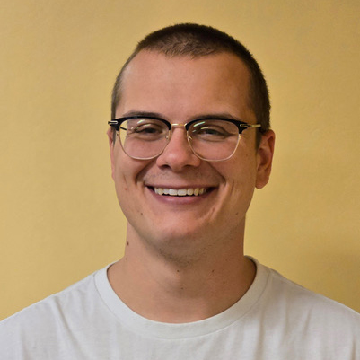 Young man smiling against a yellow background.