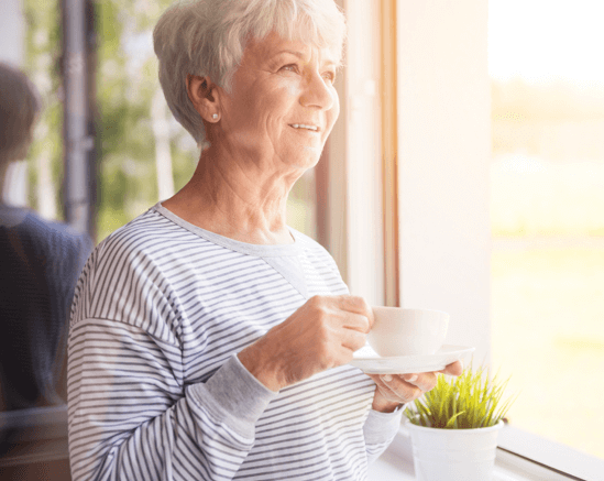 Senior woman holding a cup by the window