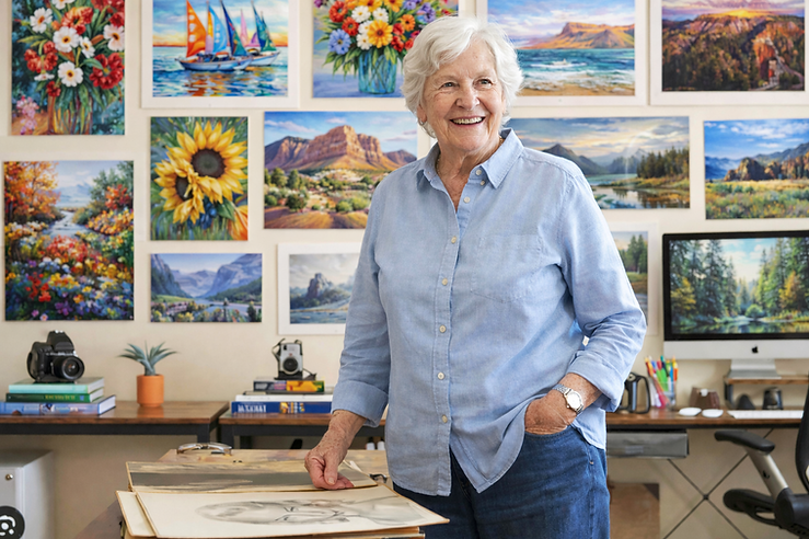 A smiling resident in an art studio surrounded by paintings
