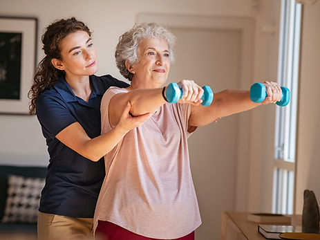 A caregiver assisting a resident with light weights