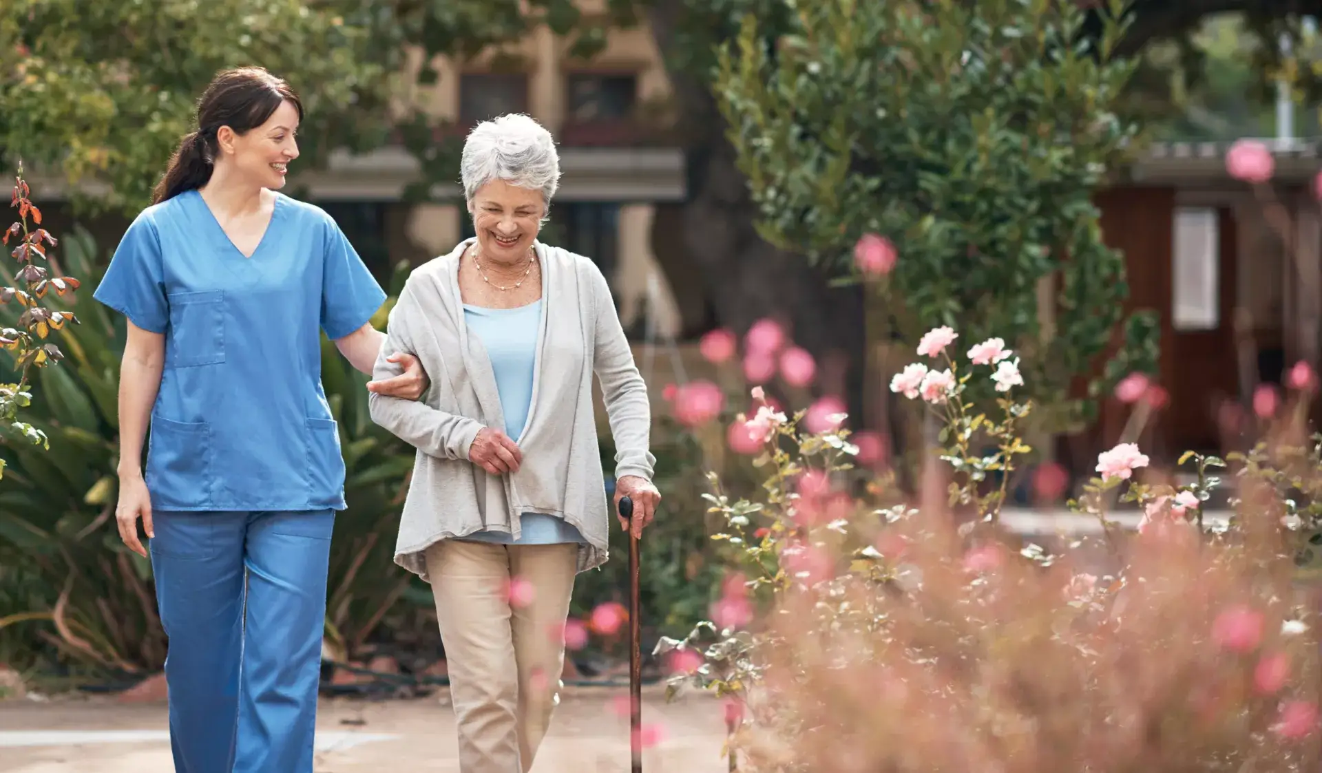 A caregiver assisting a senior woman in a garden
