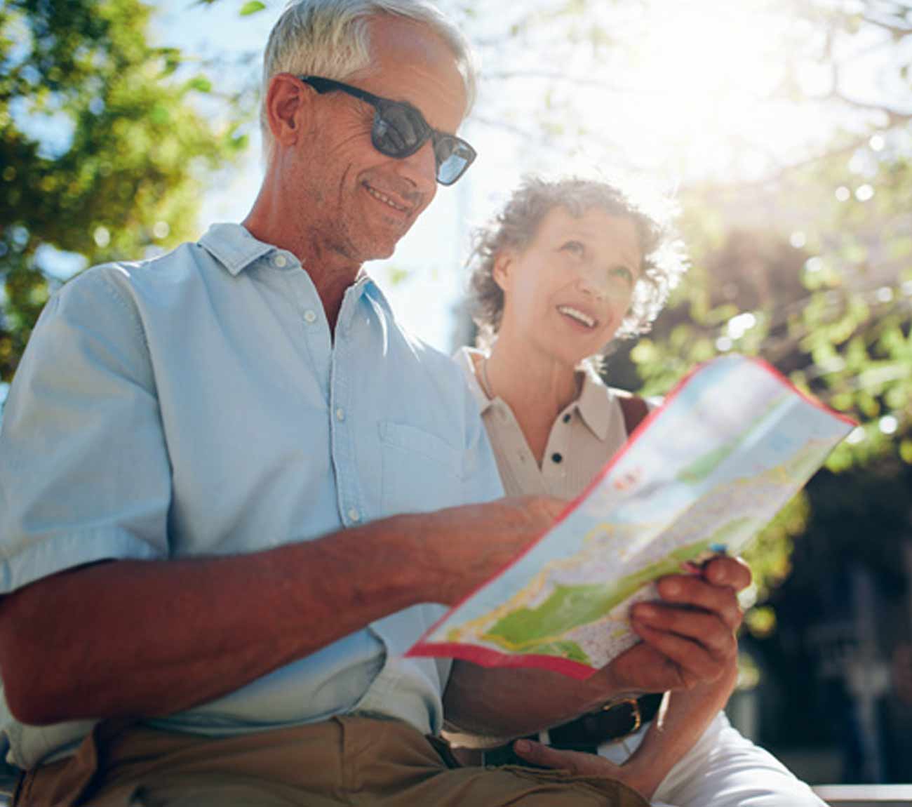 Two seniors enjoying a sunny day outdoors with a map