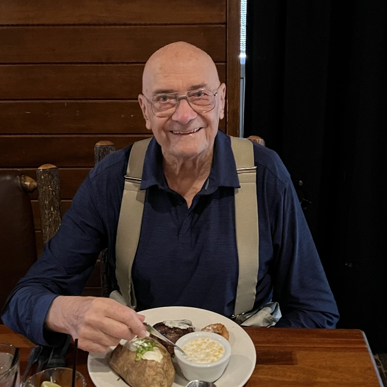 An elderly man enjoying a meal at a dining table