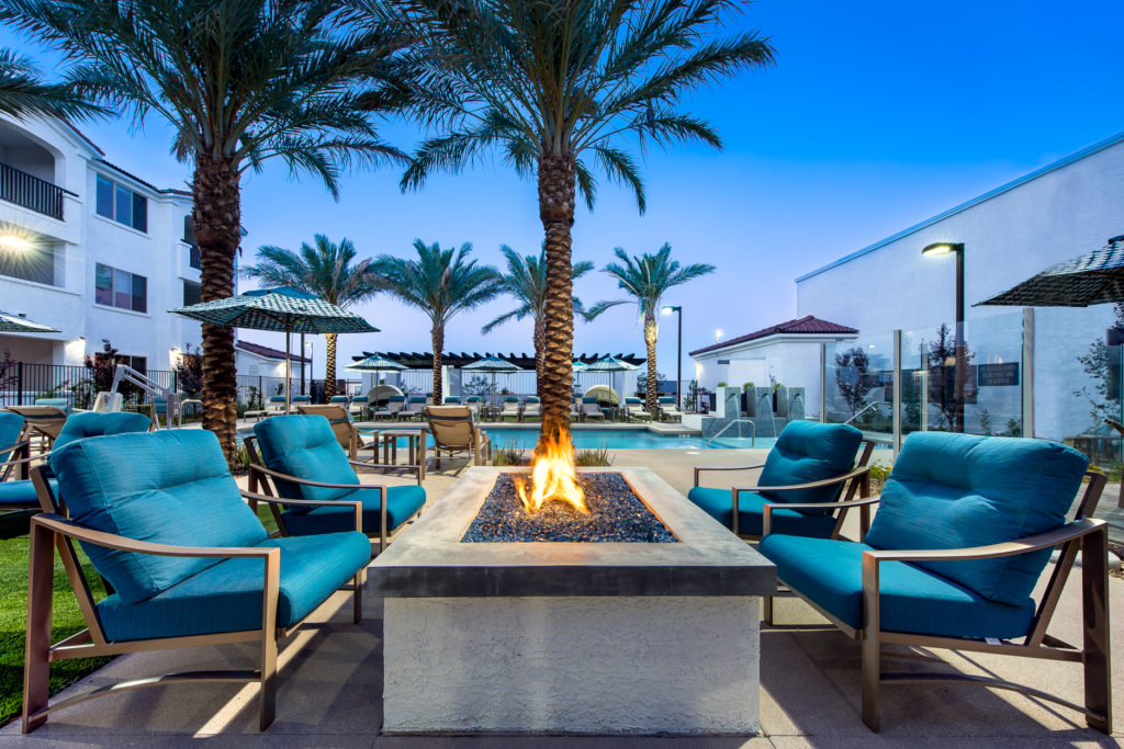 Outdoor fire pit area with seating and palm trees