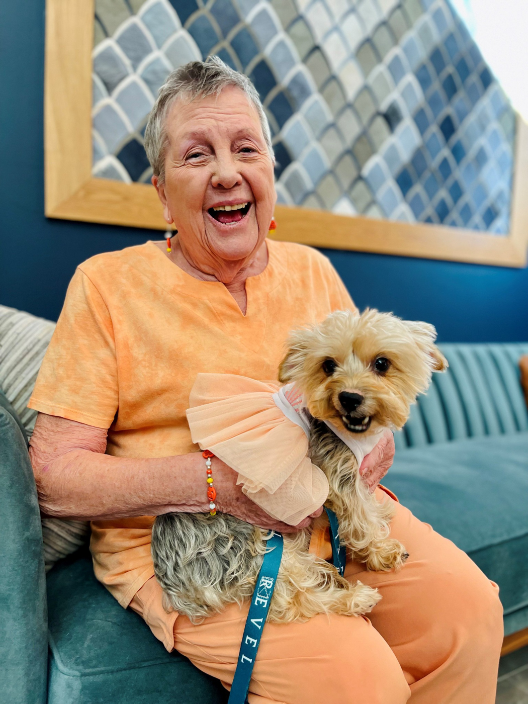 Resident happily holding a small dog in a common area