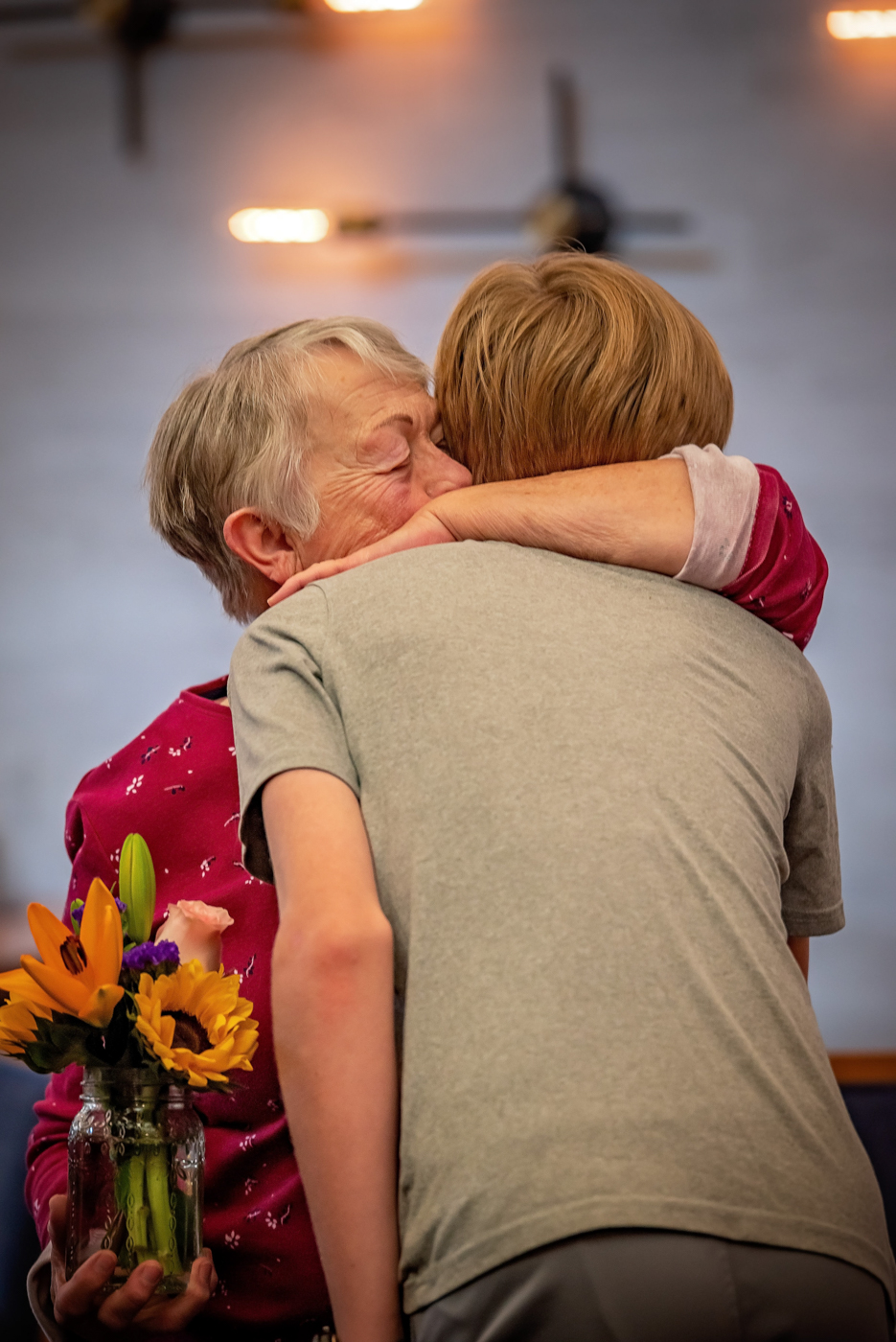Emotional hug between a resident and a visitor with flowers
