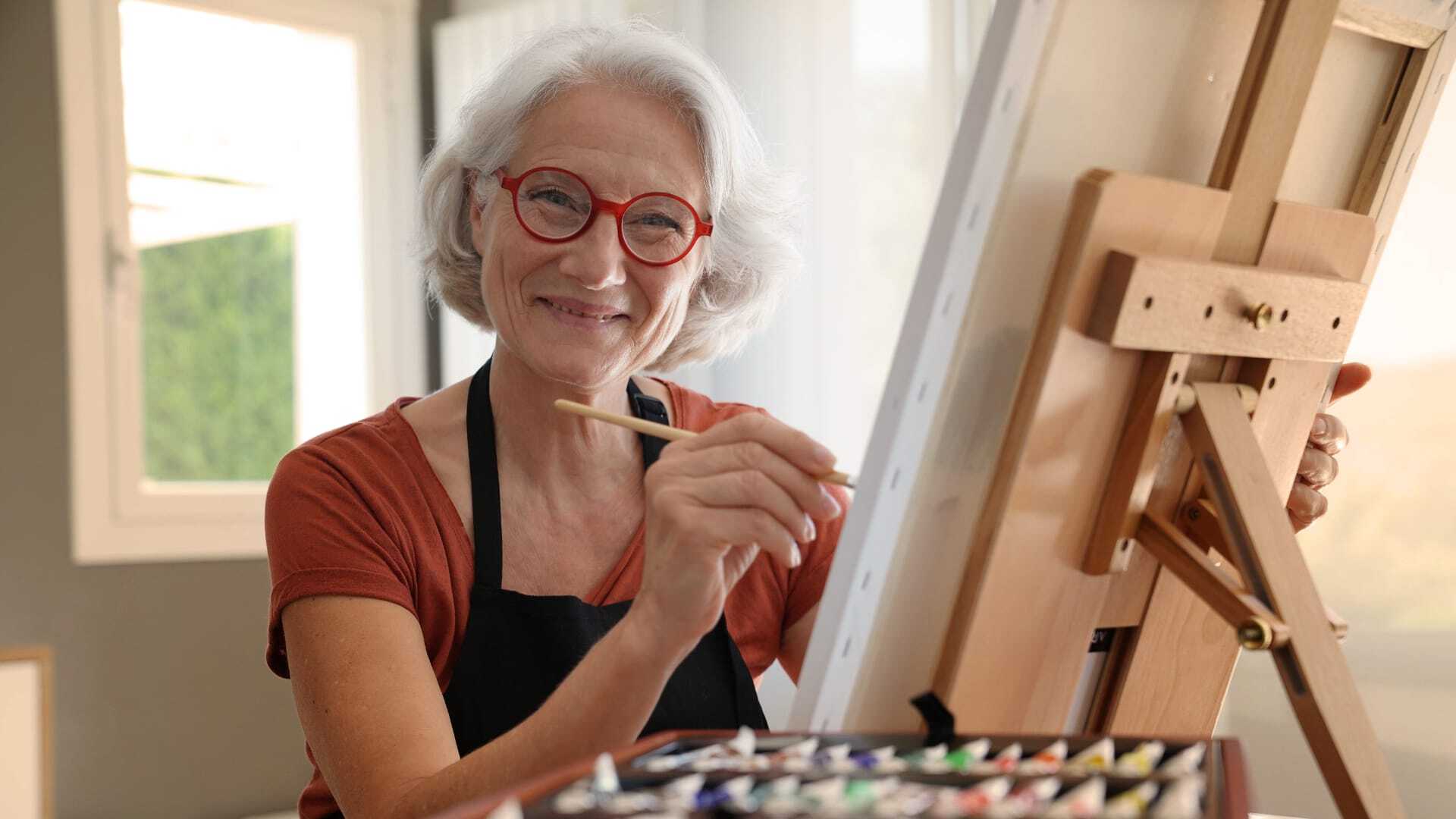 Senior resident painting at an easel in a bright room