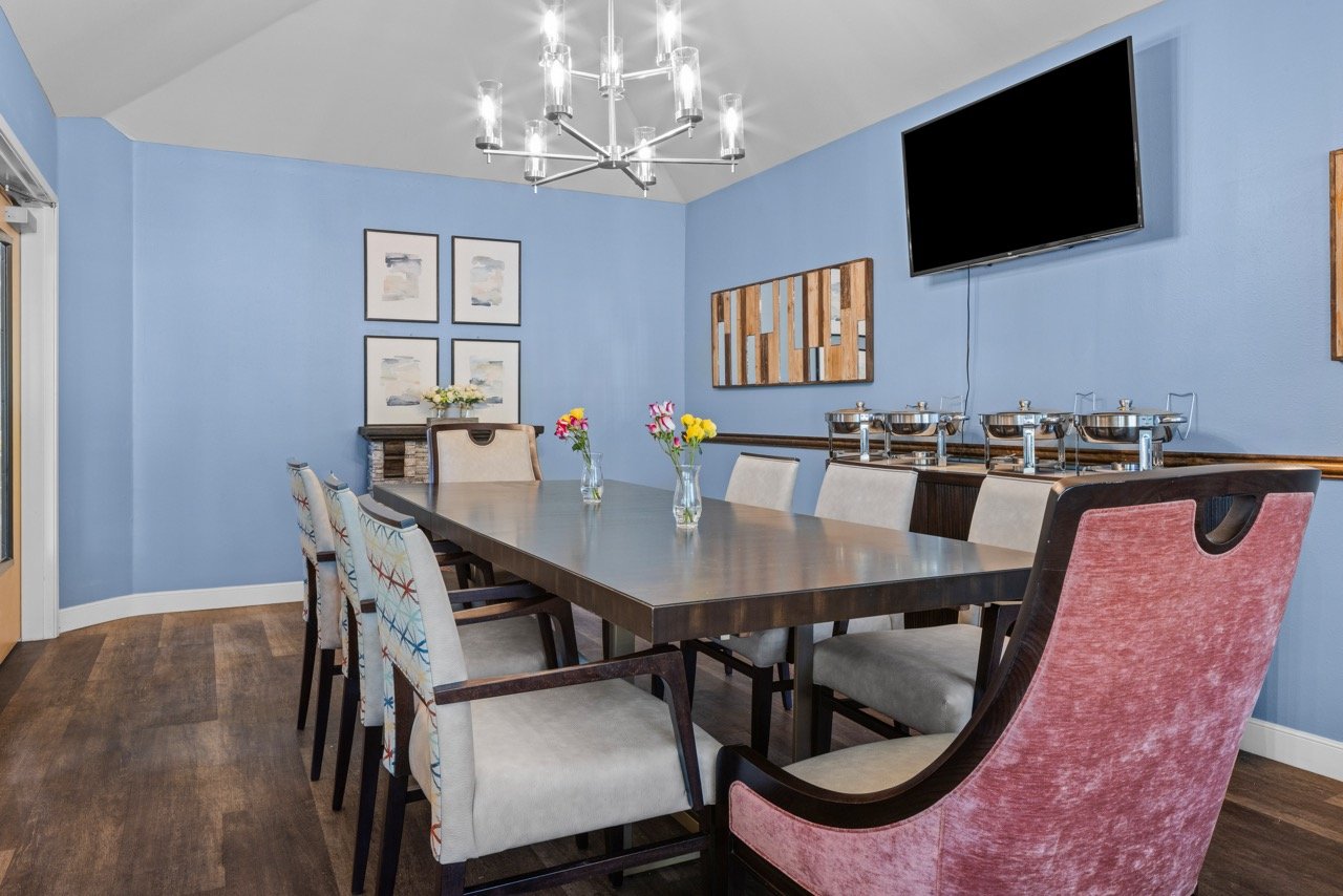 Bright dining room with a large table and flowers.