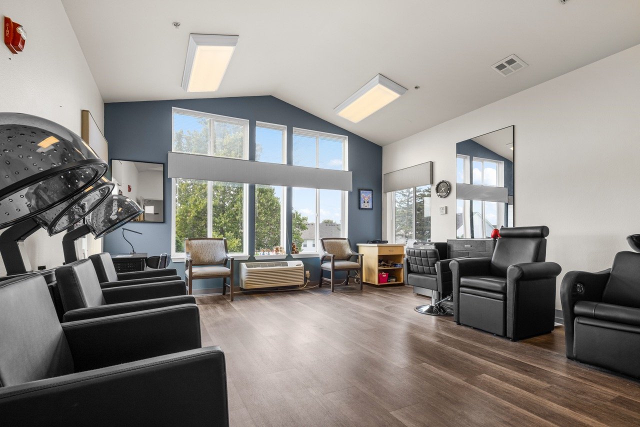 Interior of a salon area with black chairs and large windows