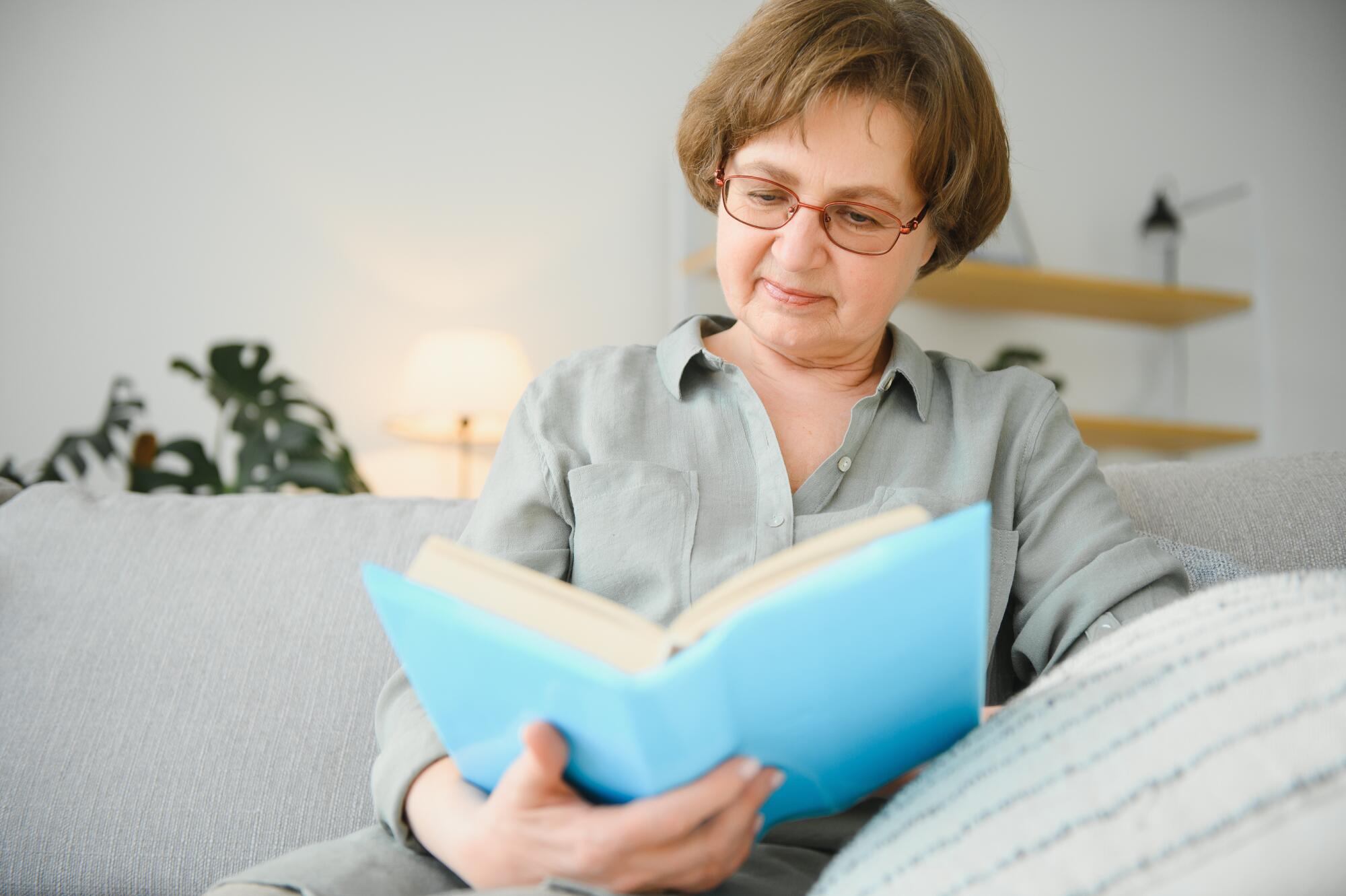 A senior woman reading a book in a cozy indoor setting