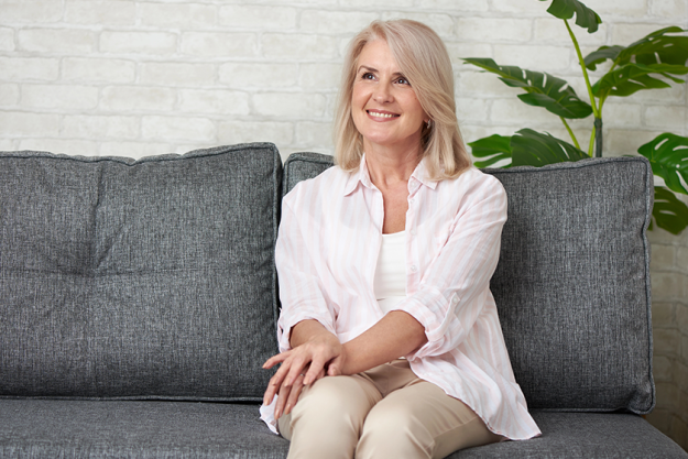 Senior woman smiling on a couch in a bright living area