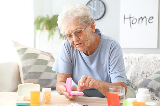 An elderly woman managing her medication in a bright room