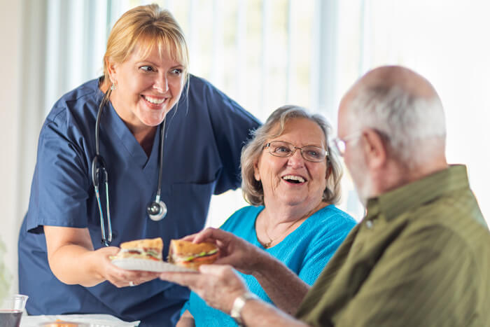Staff serving food to happy residents in a dining area