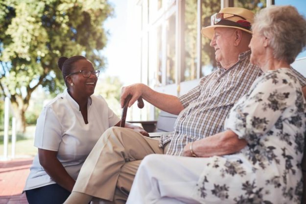 Caregiver interacting with elderly residents outdoors
