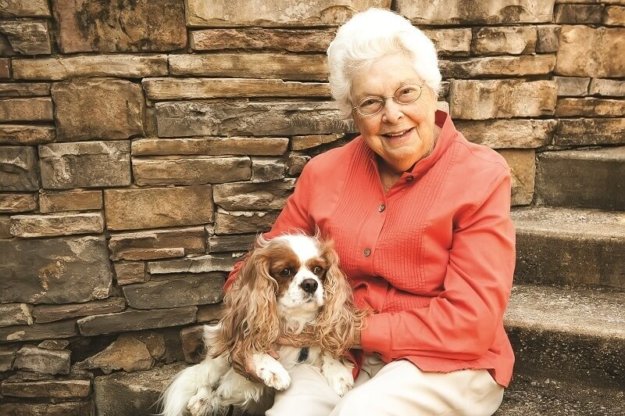 A senior woman smiling with a dog outside