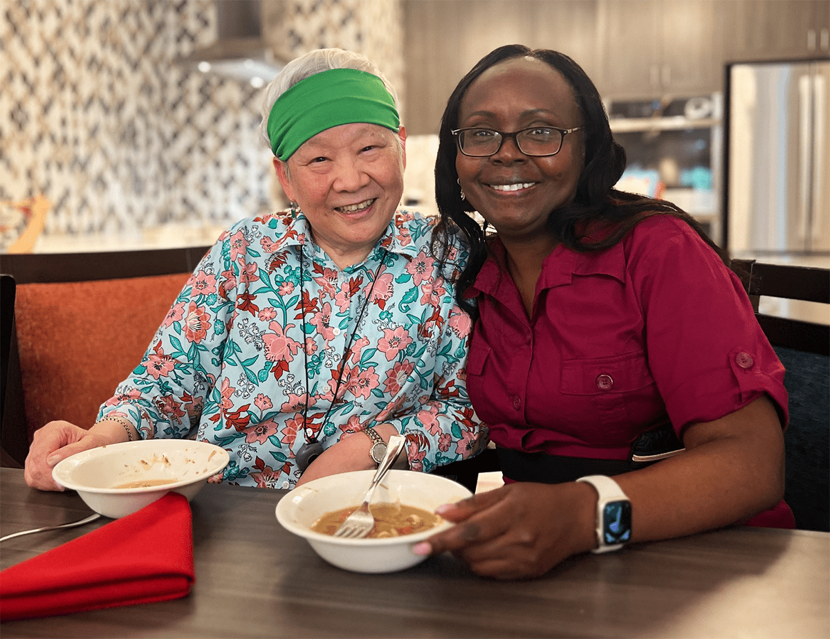 Resident and staff enjoying a meal together in a dining area