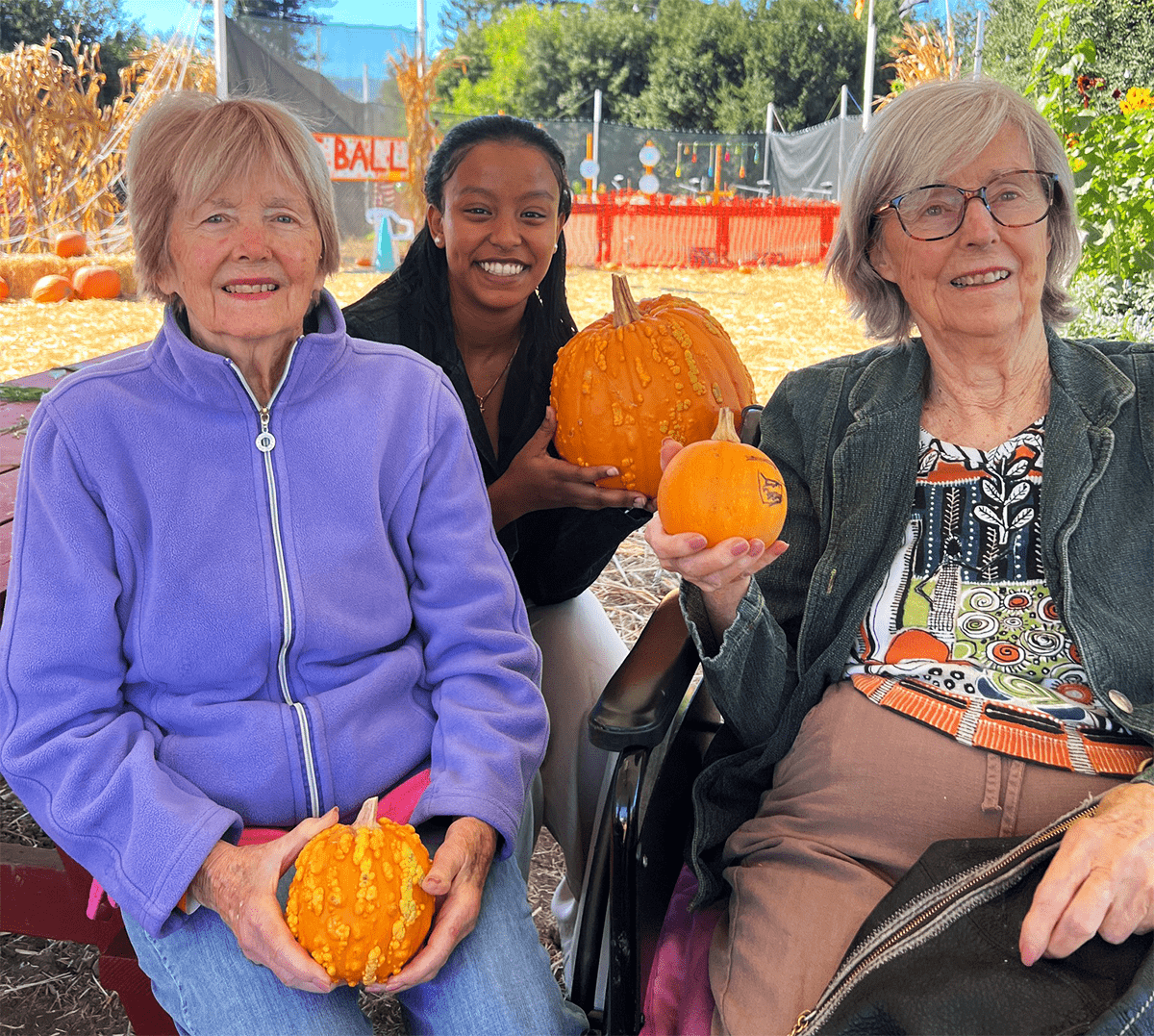 Residents and staff enjoying a pumpkin activity outdoors
