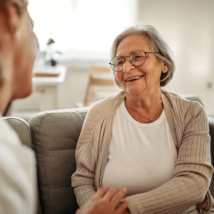Smiling elderly woman talking with caregiver