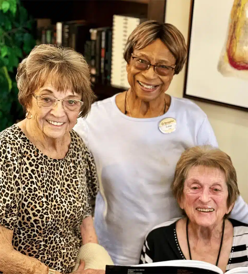 Three residents smiling together in a warm interior setting