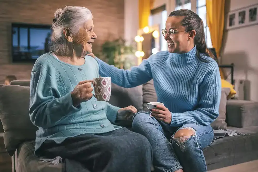 Elderly woman and caregiver sharing a warm moment indoors