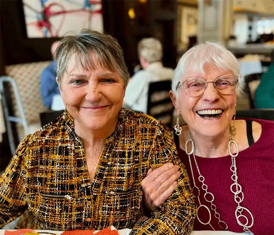 Two happy senior women smiling together in a dining area