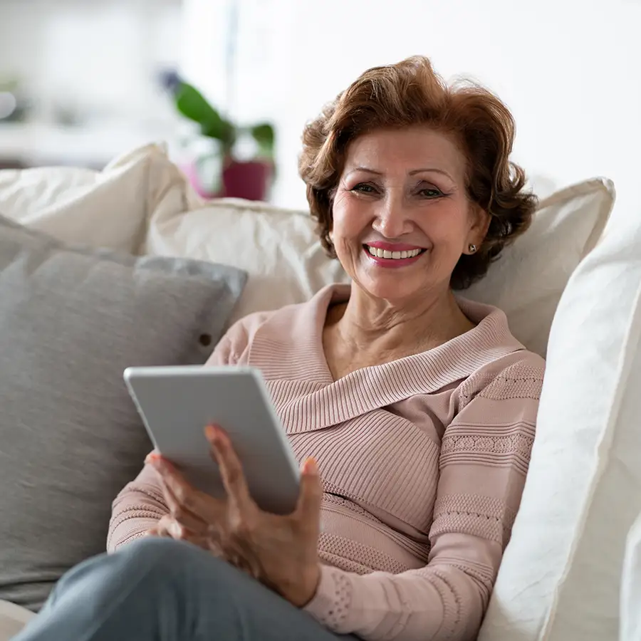 Senior woman smiling while using a tablet in a cozy setting