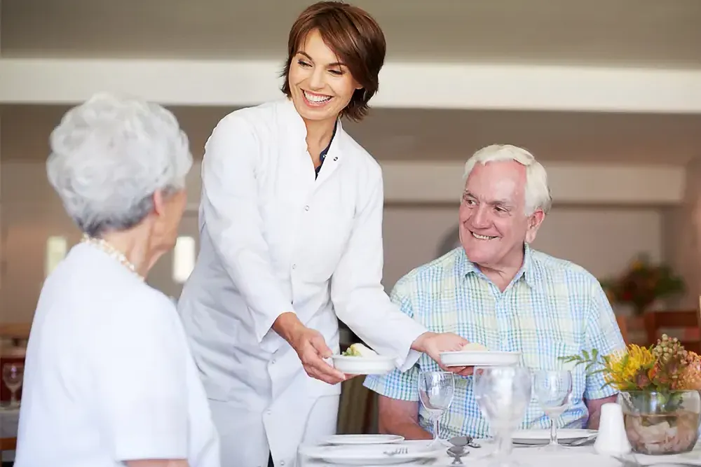 Staff serving a meal to residents in the dining room